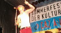 Sänger im weißen Tanktop vor Banner des Sommerfestes, Quelle: DTF