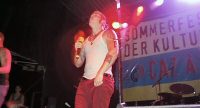 Sänger im weißen Tanktop vor Banner des Sommerfestes, Quelle: DTF