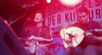 Band sitzt auf der Bühne vor Banner des Sommerfestes, Quelle: DTF