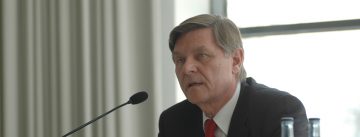 Mann im schwarzen Sakko spricht ins Mikrofon mit Blick nach vorne gerichtet