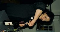 Frau im schwarzen Pullover öffnet eine Weinflasche, Quelle: DTF