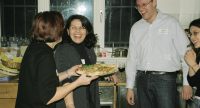 Menschen lachen hinter einem Tresen, eine Frau hält Teller mit Teigspeise drauf, Quelle: DTF