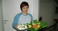 Frau im Baseballshirt trägt lächelnd eine Schale mit Salat und einen Teller mit Käse, Quelle: DTF