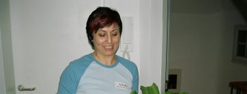 Frau im Baseballshirt trägt lächelnd eine Schale mit Salat und einen Teller mit Käse