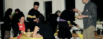 sitzende und stehende Menschen mit Essen vor sich