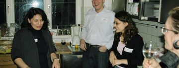 Menschen rund um Tresen lachen zusammen