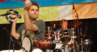 sitzender Trommler und Schlagzeuger vor Banner des Sommerfestivals, Quelle: DTF