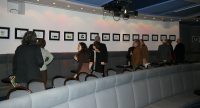 Menschen schauen auf Wand mit ausgestellten Bildern im Theatersaal, Quelle: DTF