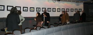 Menschen schauen auf Wand mit ausgestellten Bildern im Theatersaal