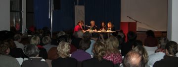 interessiertes Publikum schaut Diskussion auf der Bühne zu