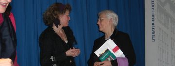 zwei Frauen unterhalten sich vor einem blauen Vorhang