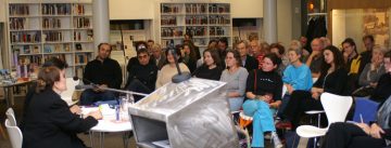 sitzendes Publikum schaut Diskussion auf der Bühne zu