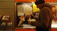 Mann liest Flyer vor Wand mit Filmpostern, Quelle: DTF