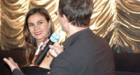 Kerim Arpad spricht zu lächelnder Dame im Abendkleid vor goldenem Vorhang, Quelle: DTF