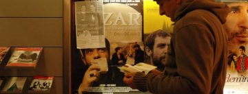 Mann liest Flyer vor Wand mit Filmpostern