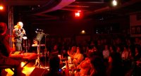 Sänger und Band auf der Bühne vor Silhouette des Publikums, Quelle: DTF