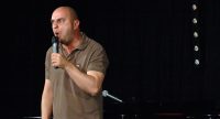 Sedar Somuncu zieht Grimassen auf der Bühne vor Silhouette des Publikums, Quelle: DTF