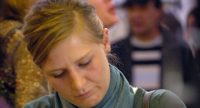 Frau im grünen Oberteil schreibt etwas an einem Stehtisch, Quelle: DTF