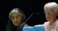 zwei Frauen sitzend nebeneinander, die ältere liest aus einem blauen Buch vor, Quelle: DTF