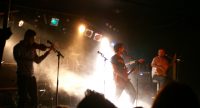 Band auf bunt beleuchteter Bühne vor Silhouette des Publikums, Quelle: DTF