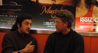 zwei Männer unterhalten sich sitzend vor Wand mit Filmpostern, Quelle: DTF