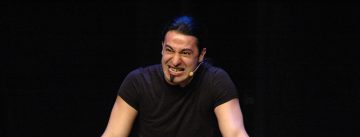 Bülent Ceylan spricht gestikulierend vor Silhouette des Publikums