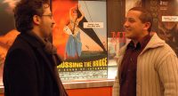 zwei Männer unterhalten sich lächelnd im Foyer vor Wand mit Filmpostern, Quelle: DTF
