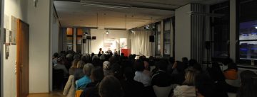 Diskussionteilnehmer*innen vor Silhouette des Publikums