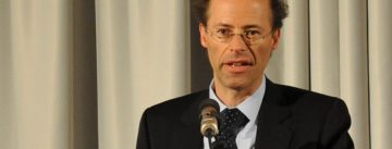 Mann im schwarzen Anzug spricht ins Mikrofon