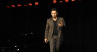 Fatih Çevikkollu geht gestikulierend über die Bühne, Quelle: DTF