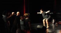 Alexandra Gauger lehnt sich in die Knie mit ausgestreckten Armen vor SIlhouette des Publikums, Quelle: DTF