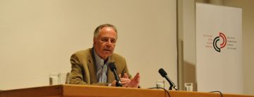 Adrian Zielcke sitzend am Holztisch neben Banner des DTF