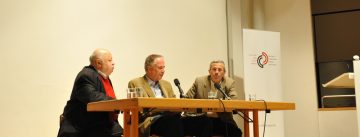 Diskussionsteilnehmer sitzend am Holztisch neben Banner des DTF