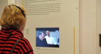 Menschen im Ausstellungsraum schauen sich ausgestellte Wände mit Text und Bilder an, Quelle: DTF