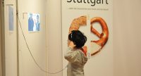 Mädchen mit Hörer in der Hand neben Ausstellungswand, Quelle: DTF