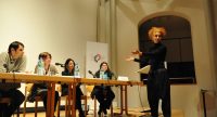 Diskussionsteilnehmer*innen sitzend am Holztisch auf dem Podium, Quelle: DTF