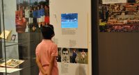 Junge mit Kopfhörer um den Kopf vor einer Ausstellungswand, Quelle: DTF