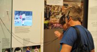 Mann mit Kopfhörer um den Kopf steht vor Ausstellungswand, Quelle: DTF