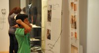 Junge mit Kopfhörer um den Kopf vor einer Ausstellungswand, Quelle: DTF