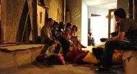 Frauen und Kinder sitzen auf Lehmbank an einer Wand in einem engen Gang, Quelle: DTF