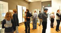 Menschen im Ausstellungsraum schauen sich ausgestellte Wände mit Text und Bilder an, Quelle: DTF