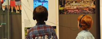 Kinder mit Kopfhörer vor Ausstellungswand