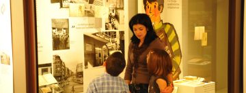 Frau mit zwei Kindern vor einer Ausstellungsvitrine