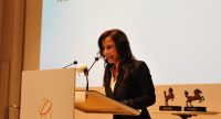 Frau steht sprechend am Rednerpult, Quelle: DTF