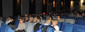 Menschen sitzend in blauen Kinosesseln