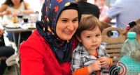 Frau mit Kopftuch hält einen misstrausisch schauenden Jungen in der linken Hand, Quelle: DTF