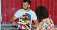 Frau steht mit vollem Teller vor jungem Mann am Grill, Quelle: DTF