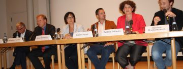 OB-Kandidat*innen sitzen an einem langen Holztisch