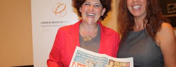 zwei Frauen lachen in die Kamera, sie halten eine türkische Zeitung
