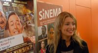 blonde Frau mit Wasserglas posiert vor Kinopostern, Quelle: DTF
